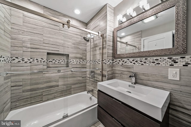 bathroom featuring tile walls, oversized vanity, and enclosed tub / shower combo