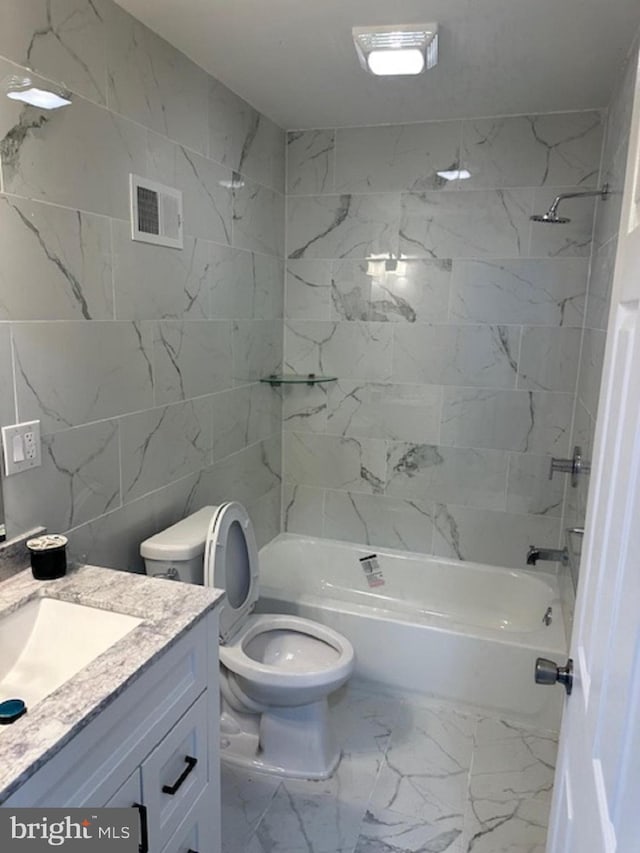 full bathroom with tile floors, vanity, tiled shower / bath combo, and toilet