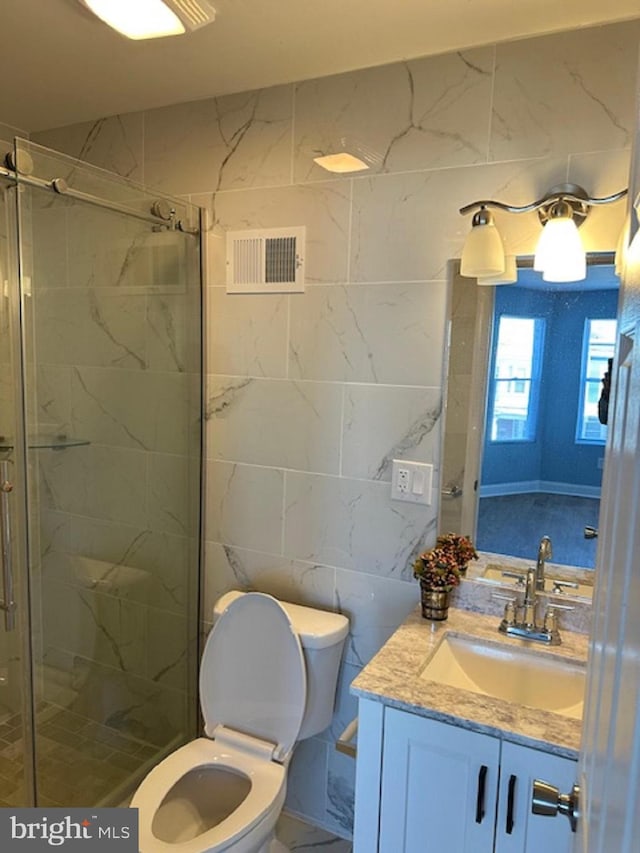 bathroom featuring vanity, a shower with shower door, toilet, and tile walls