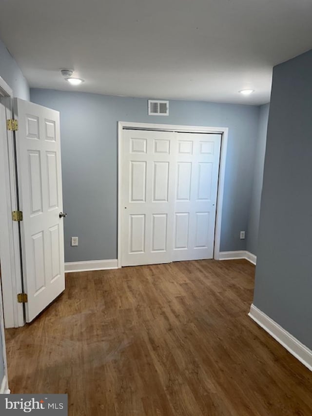 unfurnished bedroom featuring dark wood-type flooring and a closet