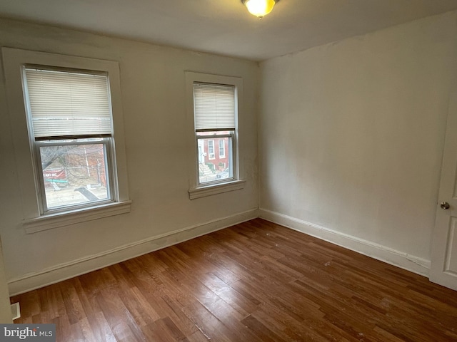 empty room featuring plenty of natural light and dark hardwood / wood-style floors