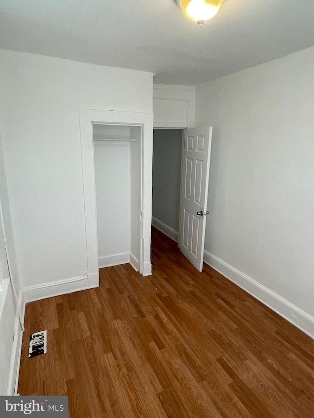 unfurnished bedroom featuring a closet and dark wood-type flooring