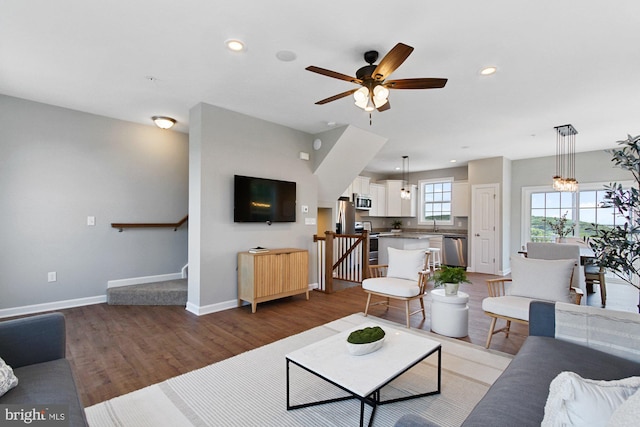 living room with wood-type flooring and ceiling fan with notable chandelier