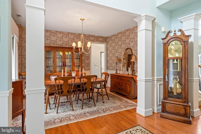 dining room featuring an inviting chandelier, hardwood / wood-style flooring, and ornate columns