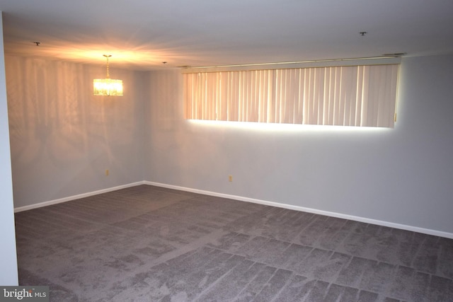 spare room with dark carpet and a notable chandelier