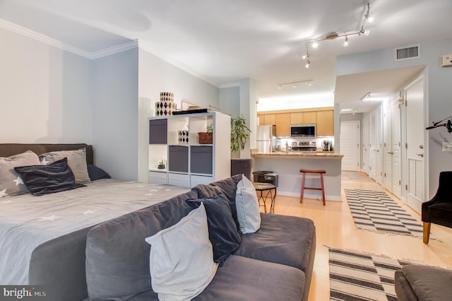 bedroom with ornamental molding, stainless steel refrigerator, light wood-type flooring, and track lighting