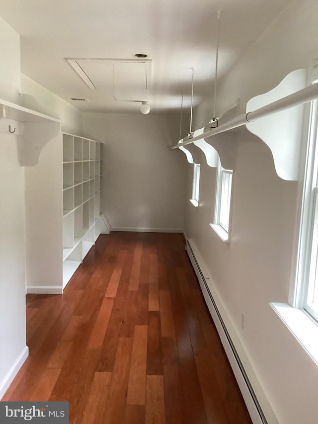 hallway with dark wood-type flooring and a baseboard heating unit