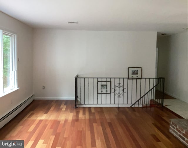 empty room with wood-type flooring and baseboard heating