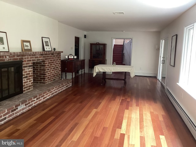 interior space featuring a baseboard heating unit, hardwood / wood-style flooring, and a fireplace