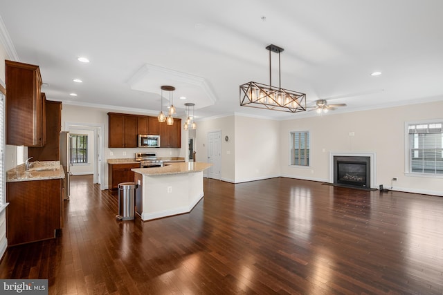 kitchen featuring crown molding, appliances with stainless steel finishes, decorative light fixtures, a kitchen island, and a breakfast bar area