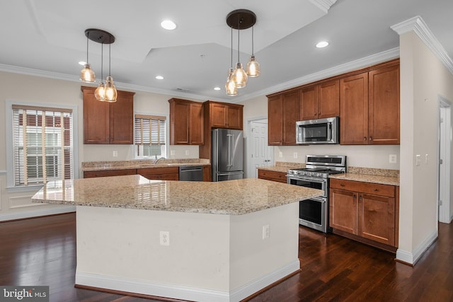 kitchen featuring ornamental molding, hanging light fixtures, a center island, and stainless steel appliances