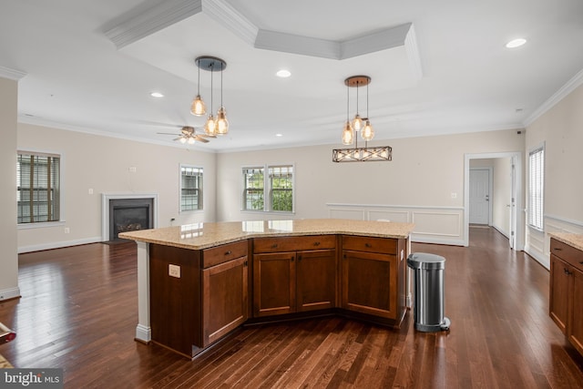 kitchen featuring dark hardwood / wood-style flooring, hanging light fixtures, a center island, and ornamental molding