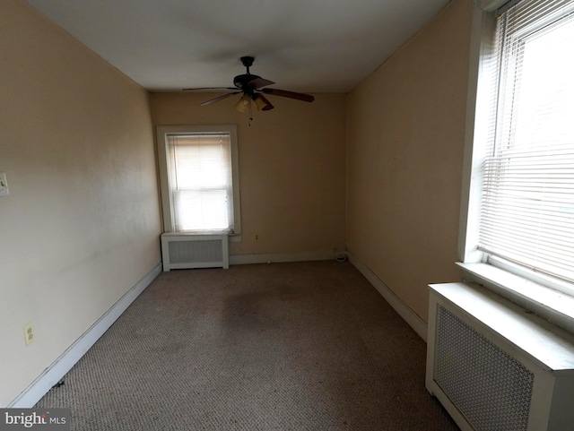 carpeted empty room featuring radiator and ceiling fan