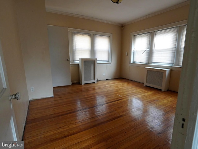 spare room featuring ornamental molding, radiator heating unit, and light wood-type flooring