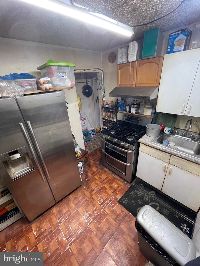 kitchen featuring a textured ceiling, stainless steel appliances, and sink