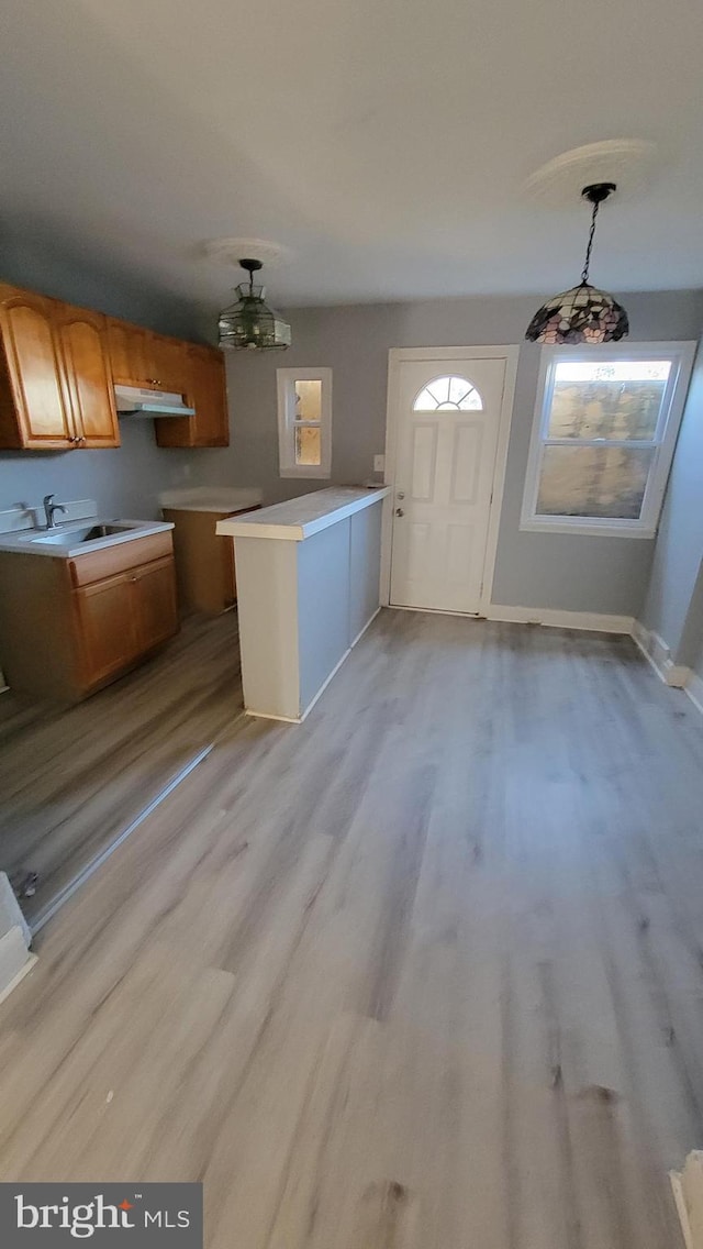 kitchen featuring hanging light fixtures, sink, kitchen peninsula, and hardwood / wood-style flooring