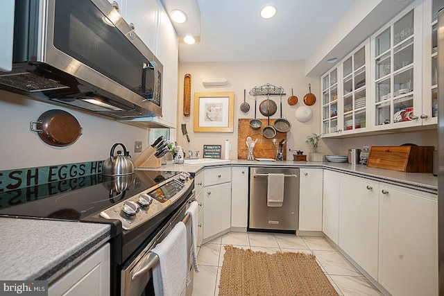 kitchen featuring appliances with stainless steel finishes, light tile floors, and white cabinets