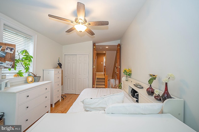 bedroom featuring lofted ceiling, light hardwood / wood-style floors, ceiling fan, and a closet