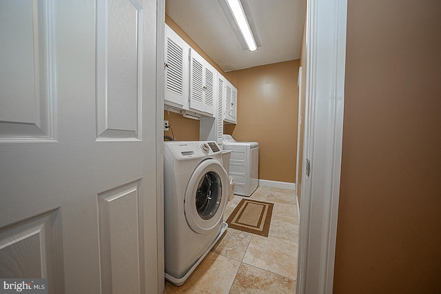 clothes washing area featuring cabinets, independent washer and dryer, and light tile flooring