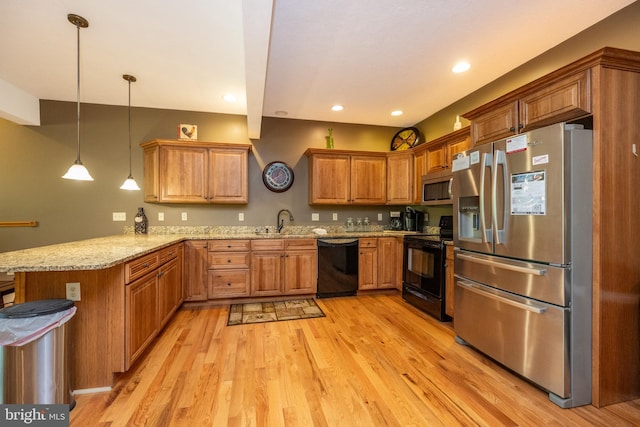 kitchen with light wood-type flooring, pendant lighting, black appliances, and light stone countertops