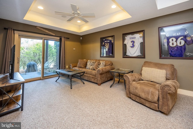 carpeted living room featuring ceiling fan and a raised ceiling