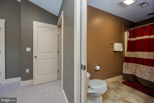 bathroom featuring lofted ceiling, tile floors, and toilet