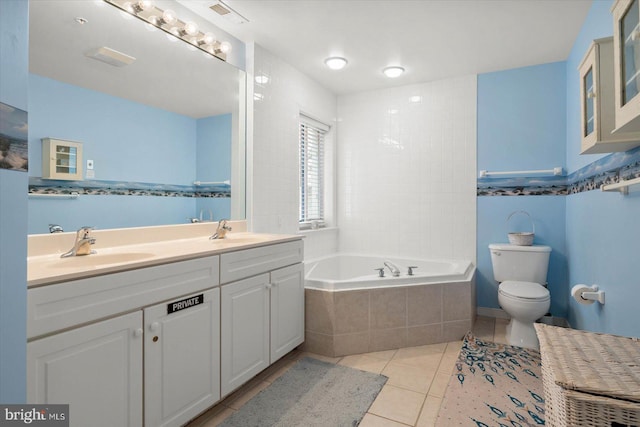 bathroom featuring tile patterned floors, vanity, tiled tub, and toilet