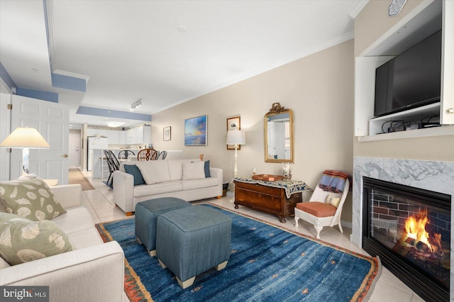 living room with a premium fireplace, light tile patterned floors, and crown molding