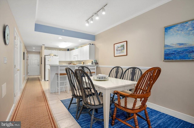 tiled dining room with track lighting and crown molding