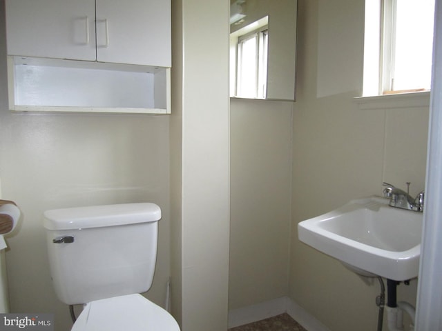 bathroom with toilet, plenty of natural light, and sink