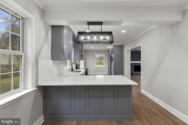 kitchen with kitchen peninsula, sink, decorative light fixtures, dark wood-type flooring, and gray cabinetry