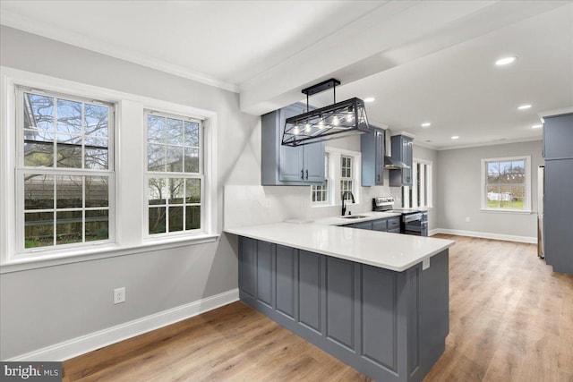 kitchen with kitchen peninsula, decorative light fixtures, light hardwood / wood-style floors, electric stove, and sink