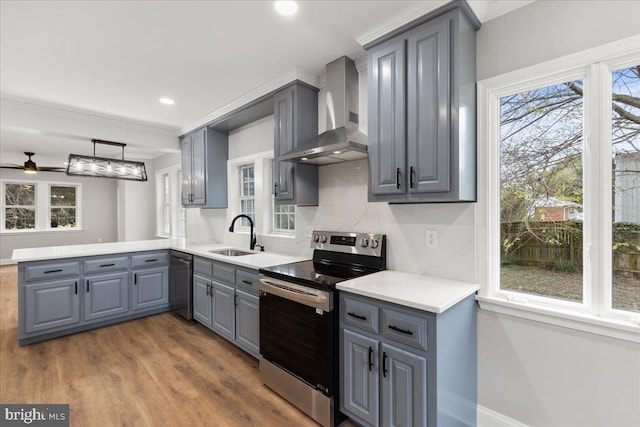 kitchen featuring ceiling fan, wall chimney range hood, gray cabinets, hardwood / wood-style floors, and stainless steel range with electric stovetop