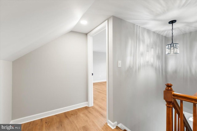 hall featuring a chandelier, vaulted ceiling, and light wood-type flooring