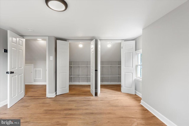 unfurnished bedroom with a spacious closet and light hardwood / wood-style floors