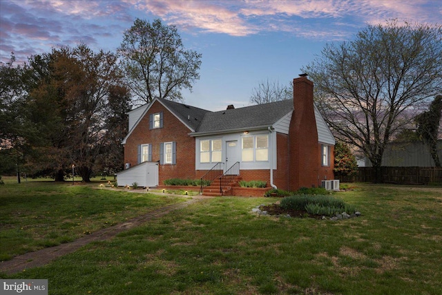 view of front of house with central air condition unit and a lawn