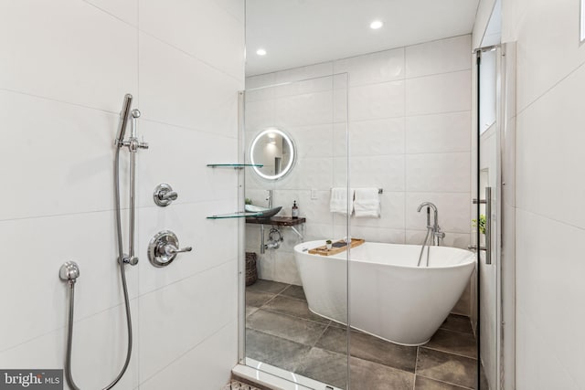 bathroom with tile walls, independent shower and bath, and tile flooring