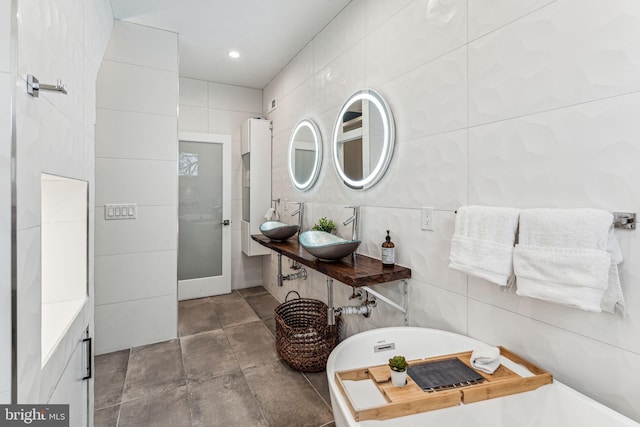 bathroom with tile flooring, sink, tile walls, and a bathtub