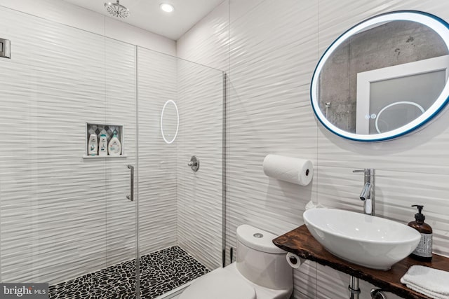 bathroom featuring a shower with door, vanity, toilet, and tile walls