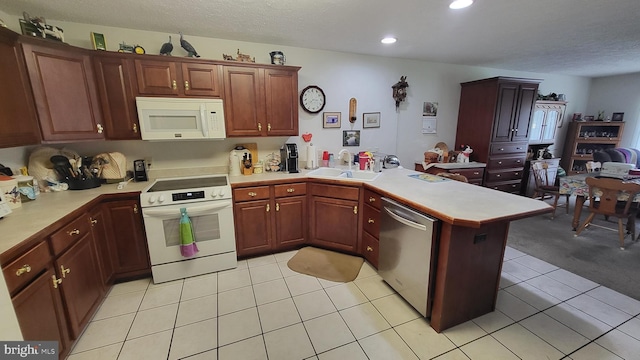 kitchen featuring kitchen peninsula, light carpet, white appliances, and sink