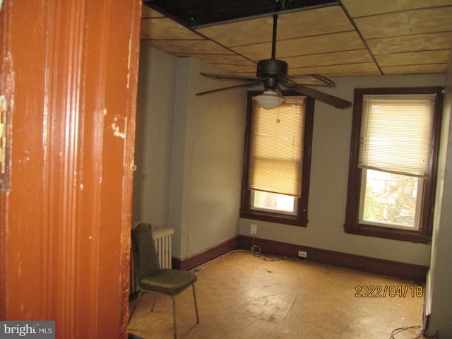 empty room with concrete flooring, a drop ceiling, and ceiling fan