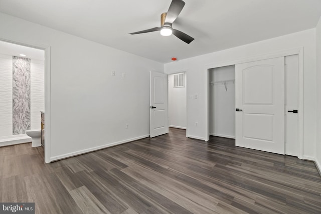 unfurnished bedroom featuring a closet, ensuite bath, dark hardwood / wood-style floors, and ceiling fan