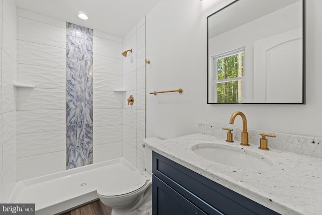 bathroom featuring vanity, tiled shower, and toilet