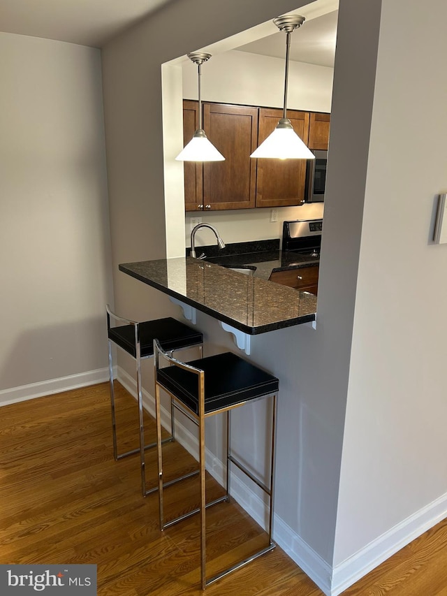 kitchen with a kitchen bar, dark hardwood / wood-style flooring, hanging light fixtures, and sink