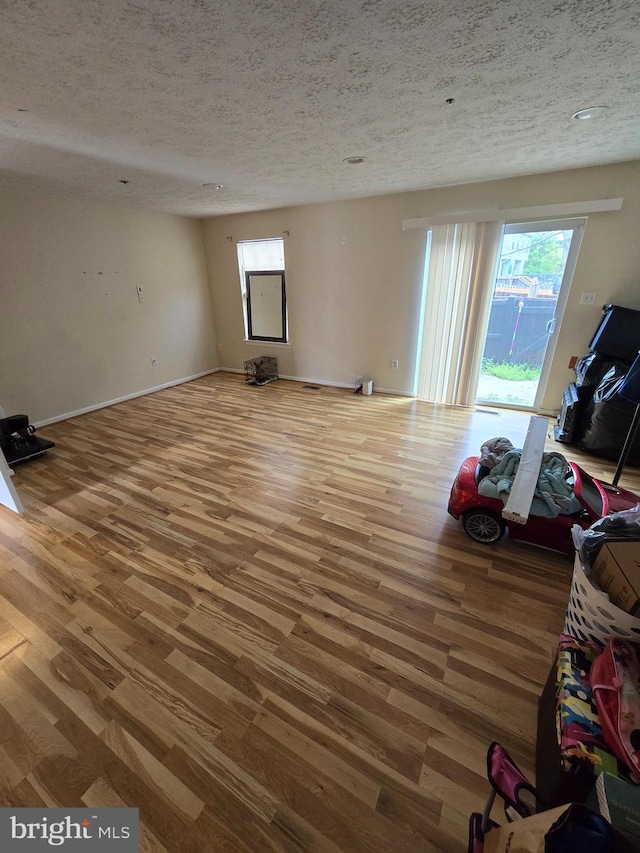 unfurnished living room featuring hardwood / wood-style floors and a textured ceiling