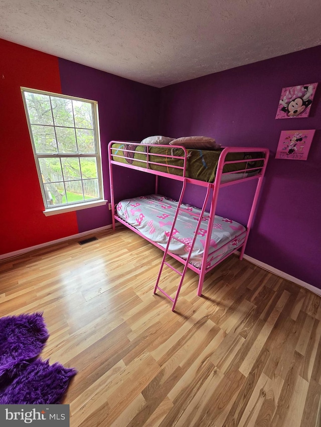 bedroom with wood-type flooring and a textured ceiling