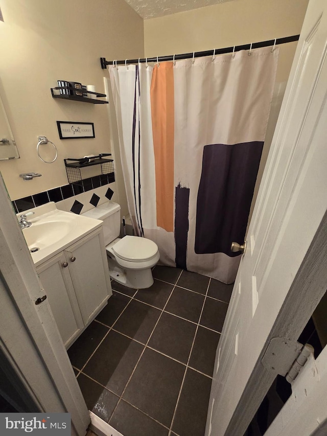 bathroom featuring tile patterned floors, vanity, toilet, and walk in shower