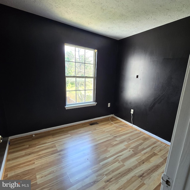 unfurnished room featuring light wood-type flooring and a textured ceiling