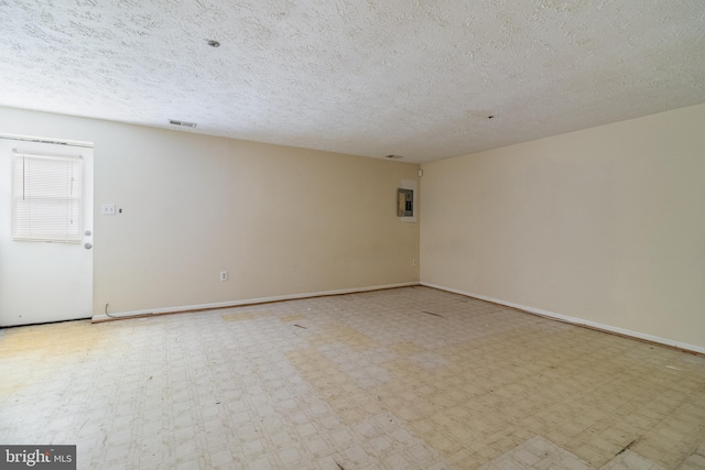 unfurnished room featuring electric panel and a textured ceiling