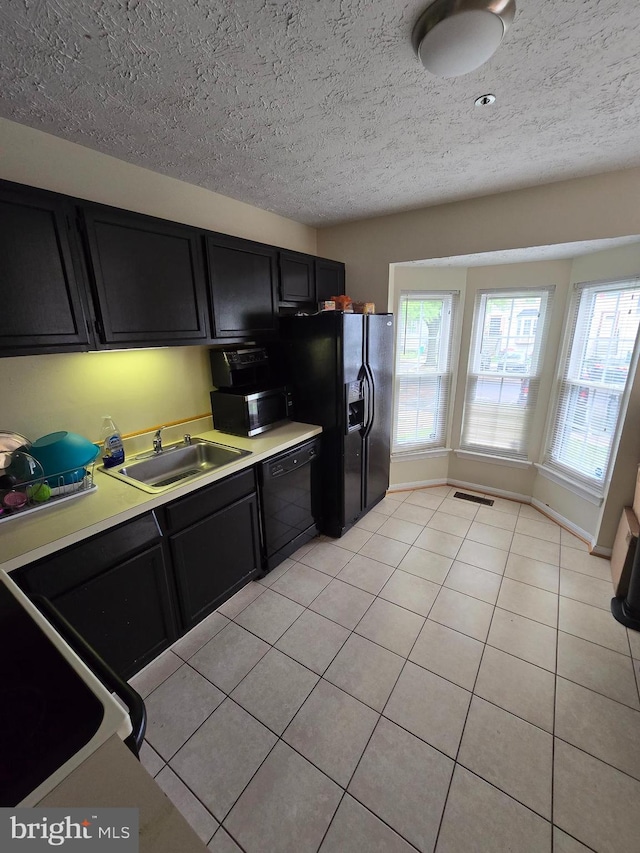 kitchen with black appliances, light tile patterned floors, sink, and a textured ceiling